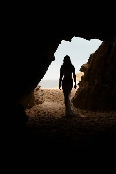 美しく セクシーな女性は立ち去ります 洞窟の中でウェディング ドレスで体のシルエット — ストック写真