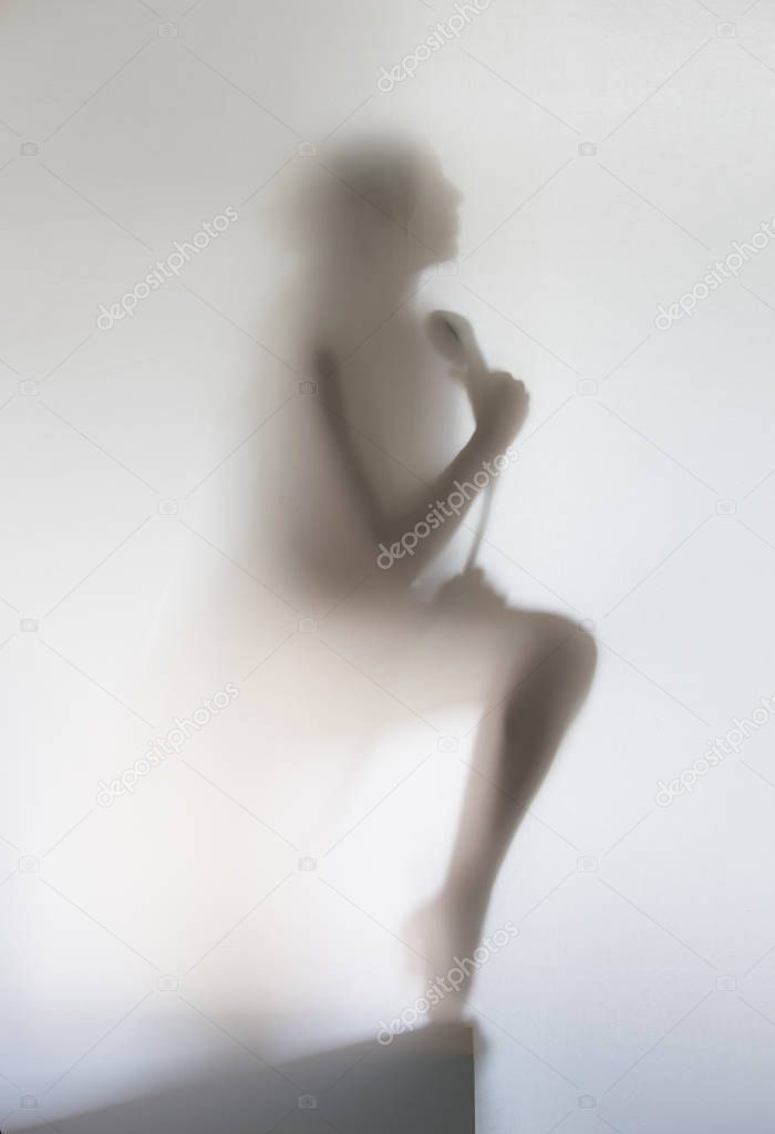 Silhouette of a beautiful woman in bathroom with shower, behind a curtain