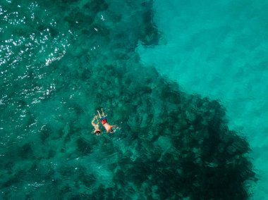Hint Okyanusu 'nun ortasında yüzen çift, mercan resifleri, yeşil su, yukarıdan. Kuş bakışı. 