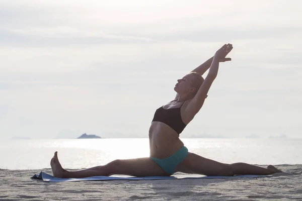 Mujer joven practica yoga en una playa al atardecer —  Fotos de Stock