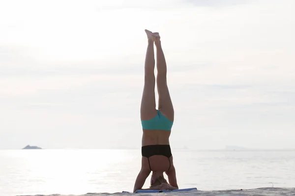 Giovane donna pratica yoga su una spiaggia al tramonto — Foto Stock