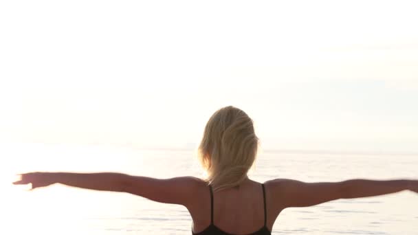 Счастливая молодая женщина практикующая йогу на пляже на закате . — стоковое видео