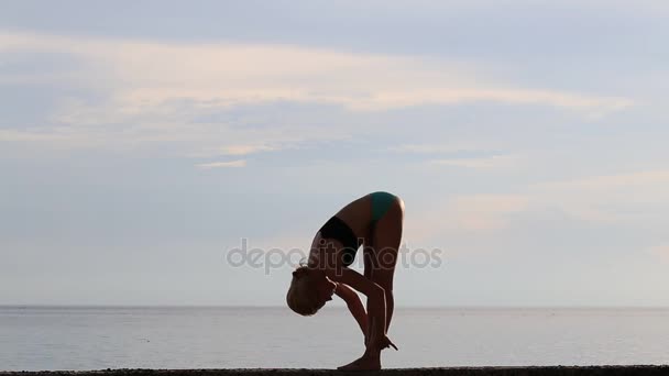 Glückliche junge Frau praktiziert Yoga am Strand bei Sonnenuntergang. — Stockvideo