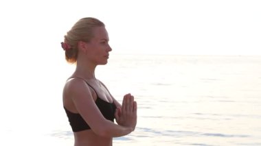 Mutlu genç kadın batımında sahilde Yoga uygulamak. Sağlıklı aktif yaşam tarzı kavramı