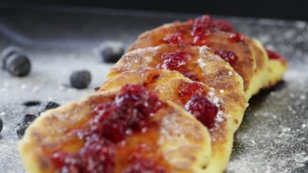 Rotation healthy homemade cheese pancakes with raspberry jam on black background — Stock Video