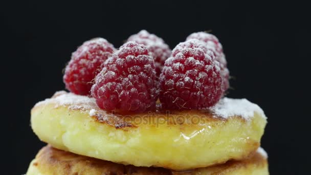 Rotation healthy homemade cheese pancakes with raspberries on black background. Top fray powdered sugar — Stock Video