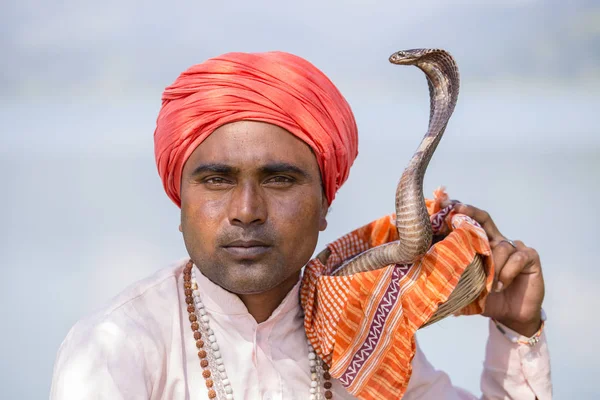 Encantador de serpientes retrato hombre adulto en turbante y cobra sentado cerca del lago. Pokhara, Nepal — Foto de Stock