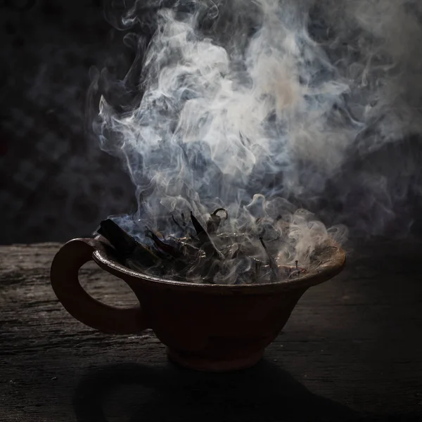 Dampfender Tonbecher mit Gewürzen auf einem Holztisch in der Straße. Stillleben schwarzer Hintergrund, nepal. — Stockfoto