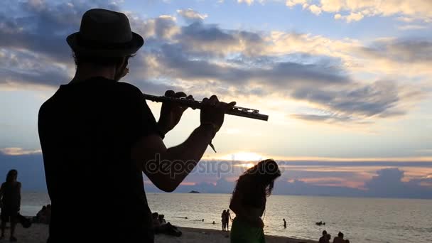 Człowiek play flet o zachodzie słońca na plaży podczas full moon party w Wyspa Koh Phangan, Tajlandia — Wideo stockowe