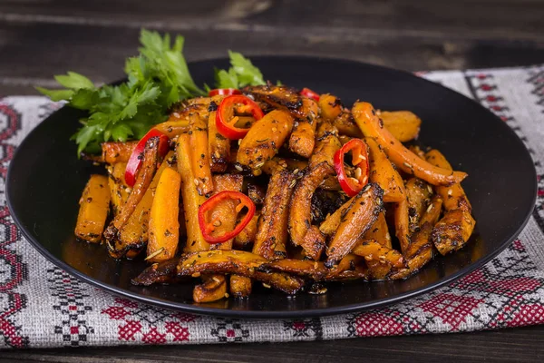 Roasted carrots in black plate, close up — Stock Photo, Image