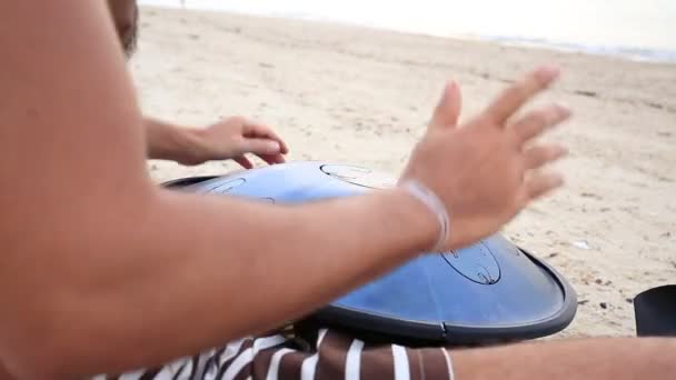 Músico tocando un instrumento llamado "Handpan" o "Hang drum" al atardecer en la playa durante una fiesta de luna llena en la isla Koh Phangan, Tailandia — Vídeos de Stock