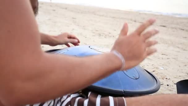 Homem músico tocando um instrumento chamado "Handpan" ou "Hang drum" ao pôr do sol na praia durante uma festa de lua cheia na ilha Koh Phangan, Tailândia — Vídeo de Stock