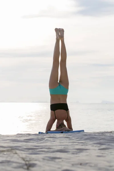 Wanita muda berlatih yoga di pantai saat matahari terbenam — Stok Foto