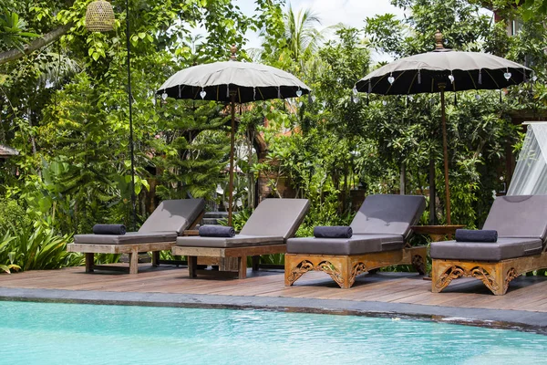 Piscina y tumbonas en jardín tropical. Isla Bali, Ubud, Indonesia —  Fotos de Stock