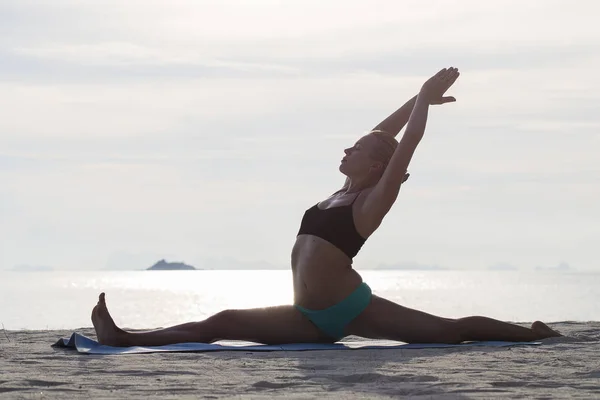 Mujer joven practica yoga en una playa al atardecer —  Fotos de Stock