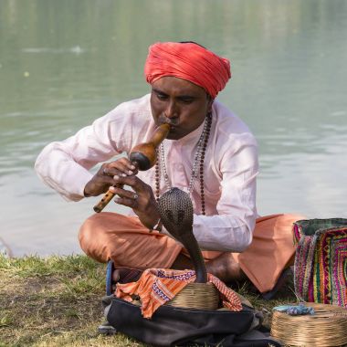 Portre çapkın yetişkin erkekte Türban ve göl kenarında oturan kobra. Pokhara, Nepal