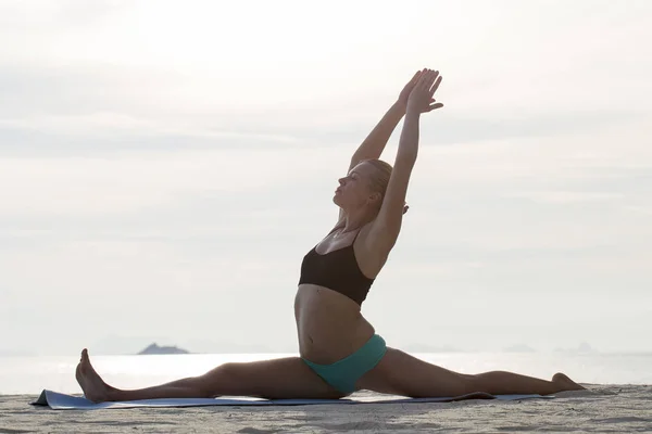 Mujer joven practica yoga en una playa al atardecer —  Fotos de Stock