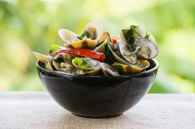 Yeşil yaprakları ve kırmızı biber siyah bir plaka ile pişirilmiş midye