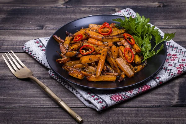 Geröstete Karotten auf schwarzem Teller, Nahaufnahme — Stockfoto