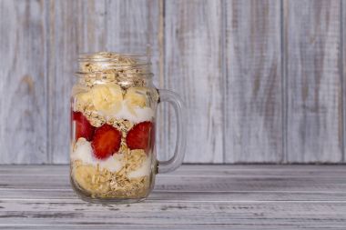 Tatlım kırmızı çilek, muz, chia tohumu, yulaf gevreği, yapılan ve yoğurt ile giyinmiş müsli