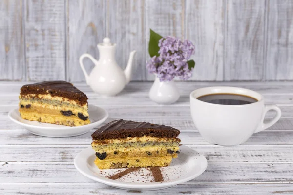 Chocolate piece of cake from biscuit dough with poppy seed, prune and walnuts and cup of coffee — Stock Photo, Image