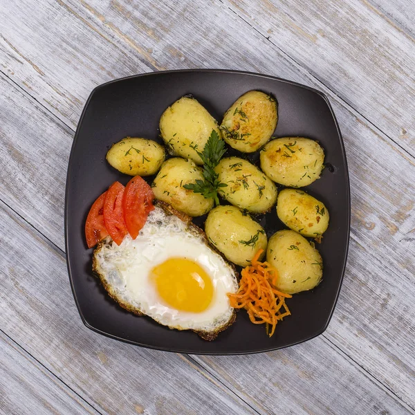 Boiled young potatoes with fried eggs, carrot and tomato. Close up — Stock Photo, Image