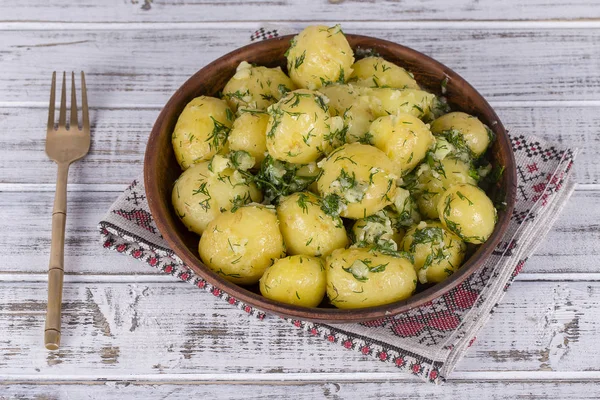 Gekookte aardappelen met dille, de knoflook en de boter in een plaat op houten tafel — Stockfoto