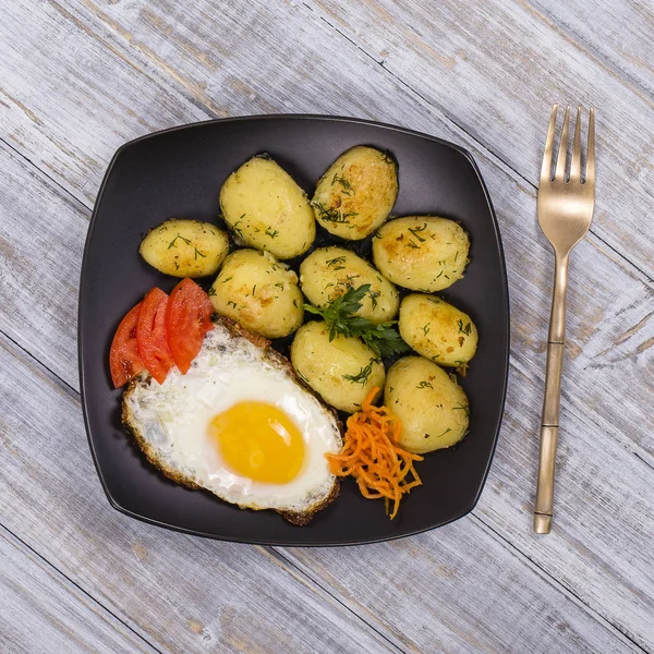 Patatas jóvenes hervidas con huevos fritos, zanahoria y tomate. De cerca. —  Fotos de Stock