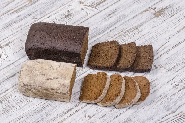 Нарізаний чорний хліб на білому дерев'яному фоні — стокове фото