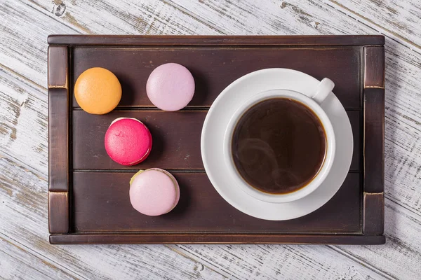 Cup of coffee and macaron cakes on tray on white wooden table. Lifestyle concept. — Stock Photo, Image