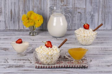 Süzme peynir, ekşi krema, süt, kırmızı çilek ve masanın üzerine bal