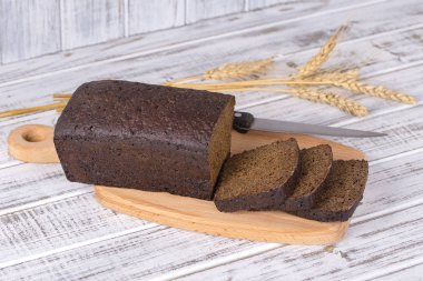 Beyaz ahşap arka plan üzerinde siyah ekmek dilimlenmiş