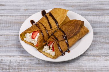 Krep ile süzme peynir, çilek, çikolata ve ahşap tablo