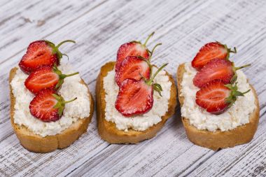 Çilek ve ahşap masa üzerinde süzme peynir sandviç kadar yakın