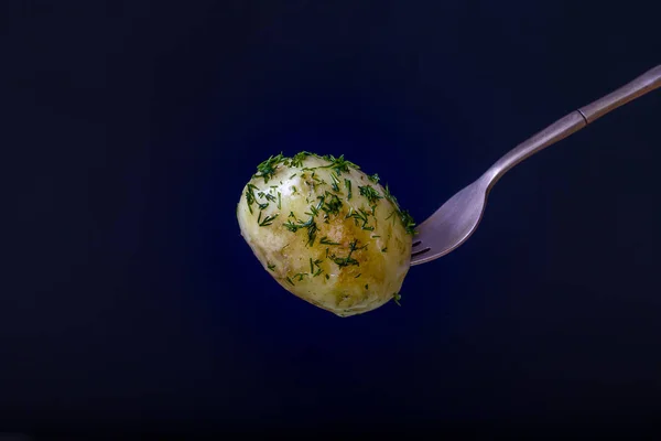 Gaffel med kokt ung potatis på svart bakgrund. Närbild — Stockfoto