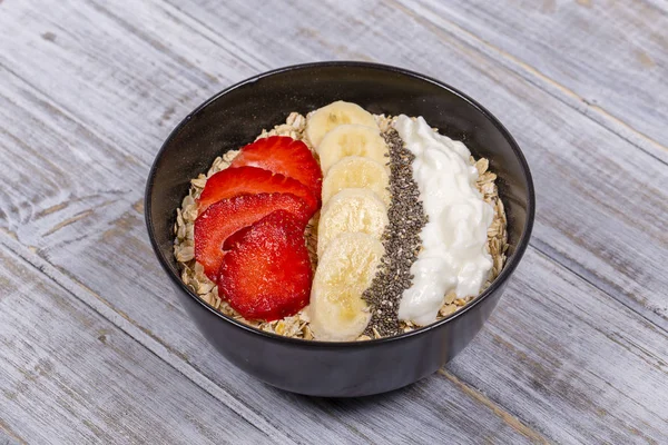 Muesli feito de morangos vermelhos, banana, sementes de chia, flocos de aveia, mel e vestido com iogurte — Fotografia de Stock