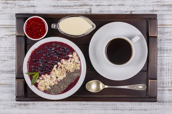 Xícara de café e muesli feito de mirtilo, sementes de chia, flocos de aveia com iogurte em uma bandeja na mesa de madeira branca. Conceito de estilo de vida. Fechar, vista superior — Fotografia de Stock