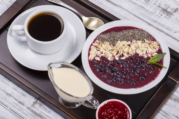 Kaffee und Müsli aus Blaubeeren, Chiasamen, Haferflocken mit Joghurt auf einem Tablett auf weißem Holztisch. Lifestyle-Konzept. Nahaufnahme, Draufsicht — Stockfoto