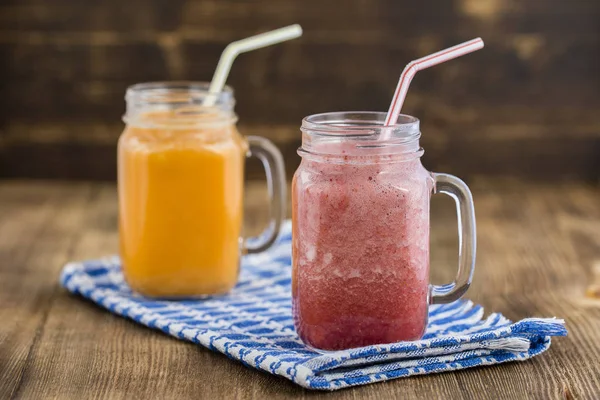 Két pohár smoothies a szamóca, málna, banán és sárgarépa-lé, citromlé, méz, közelről — Stock Fotó