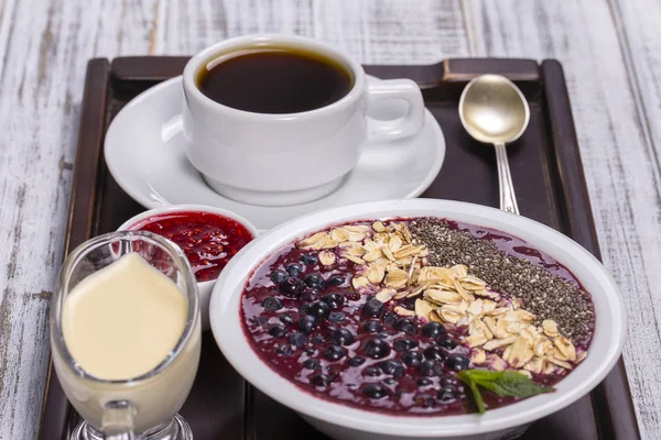 Kopp kaffe och müsli gjord av blåbär, chiafrön, havre flingor med yoghurt på en bricka på vita träbord. Livsstilskoncept. Närbild, ovanifrån — Stockfoto