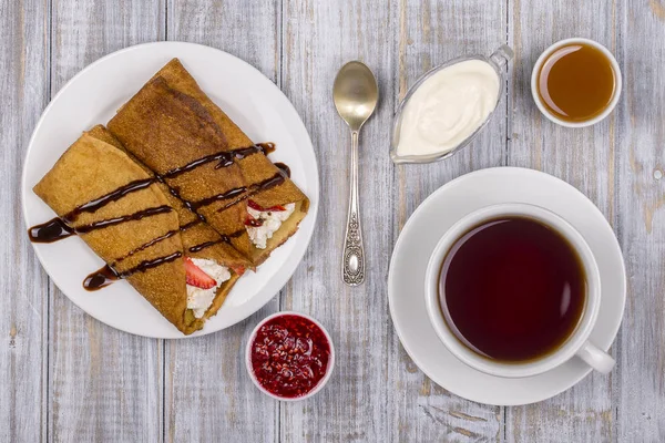 Pannkakor med keso och kopp grönt te på träbord — Stockfoto