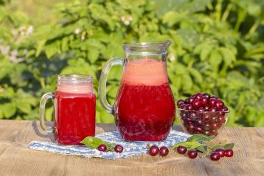 Diyet Detoks içecek temiz su buz ile kırmızı kiraz ile. Vişne suyu sürahi ve bardak ve tabak içinde Olgun Kiraz