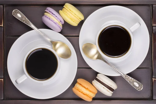 Two cups of coffee, spoon and macaron cakes on wooden tray . Lifestyle concept. Top view — Stock Photo, Image