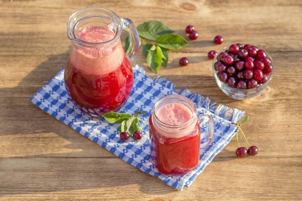 Dietary detox dryck med röda körsbär i klart vatten med is. Körsbärssaft i kanna och glas och mogna körsbär i plattan — Stockfoto