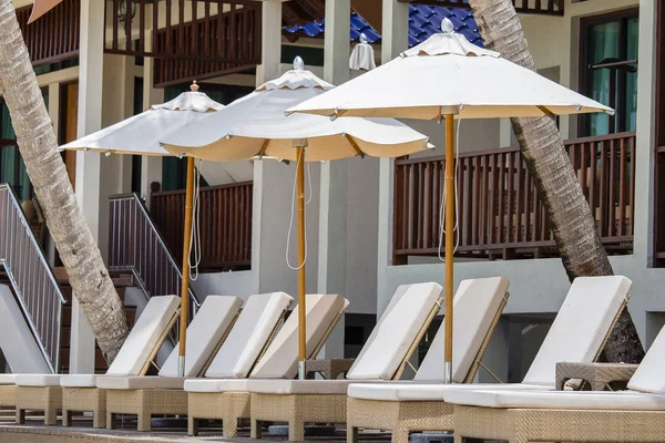 Ξαπλώστρες και ομπρέλες στην παραλία δίπλα στη θάλασσα στο τροπικό ξενοδοχείο — Φωτογραφία Αρχείου
