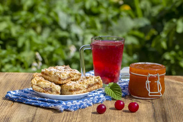 Печенье с вареньем и красный компот с вишней, клубникой, крыжовником, малиной и абрикосовым вареньем — стоковое фото