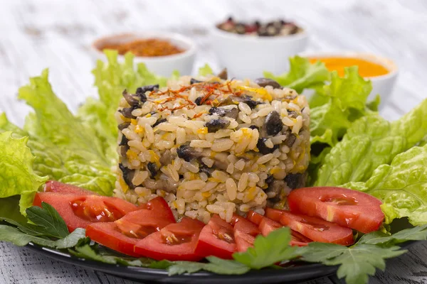 Ris med champinjoner och grön sallad lämnar på rustika bordsbakgrund — Stockfoto