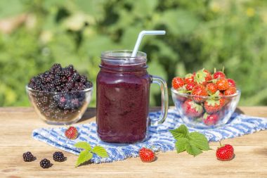Çilek, ahududu, böğürtlen ve muz suyu güler yüzlü sarsmak cam bardağa, açık havada, yakın