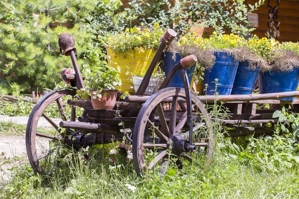 Vecchia ruota in legno con fiori in giardino. Carpazi, Ucraina — Foto Stock