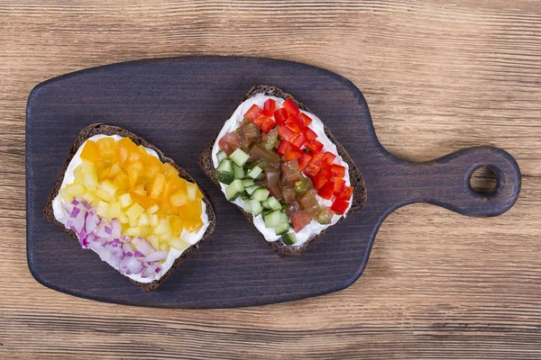 Πολύχρωμα λαχανικά σάντουιτς, κοντινό πλάνο. Φρέσκες πιπεριές, ντομάτες, αγγούρι, κρεμμύδι και τυρί σε μαύρο ψωμί. Το Top view — Φωτογραφία Αρχείου